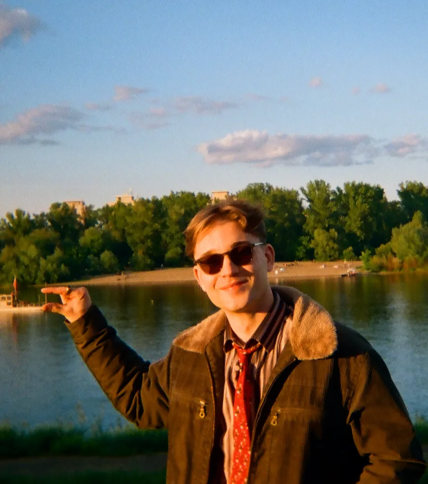 Mikołaj Glinicki w okularach przeciwsłonecznych nad wodą.